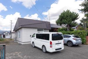 a white van parked in a parking lot in front of a house at Niko House Furano in Furano