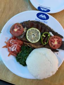 a plate of food with fish and vegetables on a table at SEGA LODGE RESORT in Sega