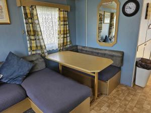 a small room with a table and a couch at Cosy caravan in Skegness