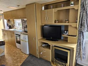 a kitchen with a tv on a desk with a fireplace at Cosy caravan in Skegness