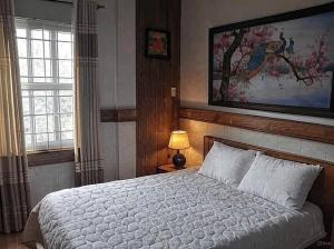 a bedroom with a bed and a painting on the wall at Hong's family house in Ấp Ngọc Hải