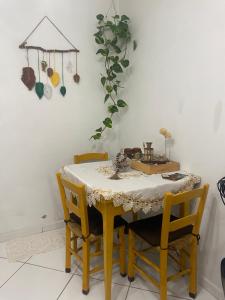 a dining room table with yellow chairs and a white wall at Residencial Melodia in Campos Novos