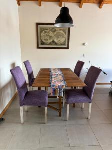 a wooden table with purple chairs and a blanket on it at Amatista dpto in San Martín de los Andes