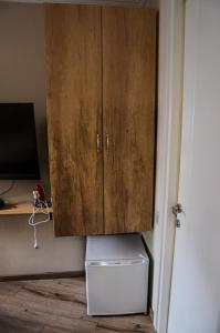 een houten kast boven een witte koelkast in een kamer bij Apartment Serpoint in Tbilisi City