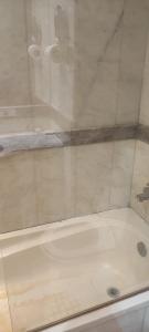 a shower with a white tub in a bathroom at محبس الجن in Al Khansāk