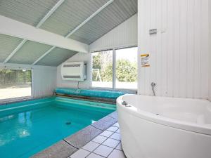 a bathroom with a tub and a swimming pool at 10 person holiday home in Hjørring-By Traum in Hjørring +10 photos