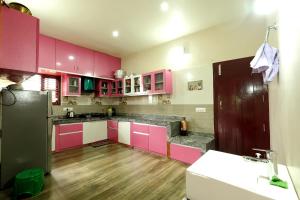 a kitchen with pink cabinets and a wooden floor at Sogadu Homestay - Full Villa, 4BH, Estate, Home Food in Sakleshpur