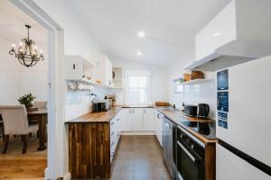 una cucina con mobili bianchi e un piano di lavoro in legno di Mygoura Cottage - Charming Country Living in Town a Mudgee