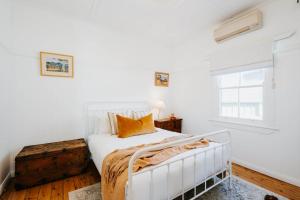 una camera da letto bianca con un letto bianco e una finestra di Mygoura Cottage - Charming Country Living in Town a Mudgee