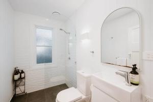 un bagno bianco con lavandino e specchio di Mygoura Cottage - Charming Country Living in Town a Mudgee Altre 27 foto