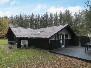 una piccola casa nera con un ponte in un cortile di Tranquil Cottage Retreat in Lokken-By Traum a Løkken