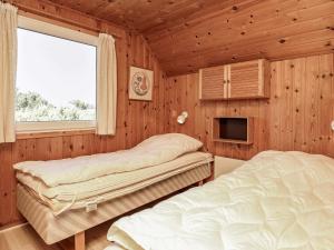 two beds in a room with wooden walls and a window at 6 person holiday home in Hvide Sande-By Traum in Hvide Sande