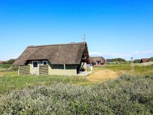 an old barn with a thatched roof in a field at 6 person holiday home in Hvide Sande-By Traum in Hvide Sande