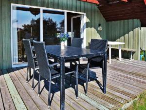 a black dining table and chairs on a deck at 6 person holiday home in Hvide Sande-By Traum in Hvide Sande