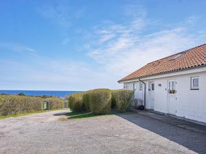 a white building with hedges in front of it at Seaside Escape in Sandkas - By Traum Ferienwohnungen in Allinge
