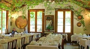 un comedor con mesas y sillas blancas y ventanas en Hotel Monte d'Oro, en Vizzavona