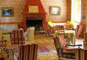 a living room with a fireplace and chairs and a table at Hotel Monte d'Oro in Vizzavona