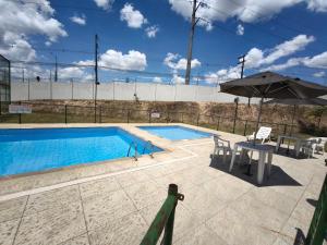 a swimming pool with a table and chairs and an umbrella at Lindo e Confortavel Apto Ideal Torquato in Manaus