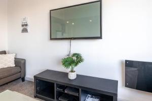 sala de estar con TV y mesa con planta en Hidden Hideaway With Harbour View - Prime location, en Wellington