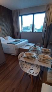 una camera d'albergo con un tavolo, sedie e un letto di Flat Região Nobre a Curitiba Altre 36 foto
