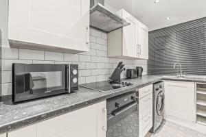 a kitchen with white cabinets and a microwave at Contractor Stays Sleeps 8 Free WiFi and Parking Near Centre Special Offer 20 Nights Plus in Nottingham +30 photos