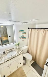 Un baño con inodoro, lavabo y espejo. en Relaxing Galveston Oceanfront Escape With Heated Pool, en Galveston