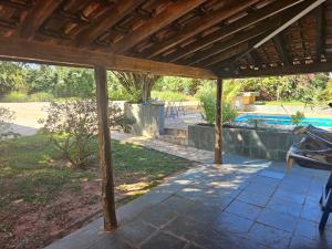 a covered patio with a table and a pool at Chácara Paraíso Country House Events in Bauru