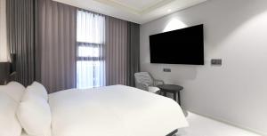 a bedroom with a white bed and a television at Labelle Hotel Premier in Gangneung