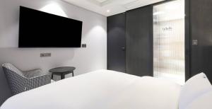 a bedroom with a bed and a flat screen tv at Labelle Hotel Premier in Gangneung