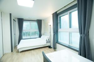 a bedroom with a bed and two windows at Yangyang Ocean Hill in Yangyang