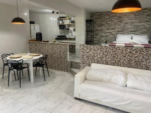 a living room with a couch and a table and a kitchen at Loft Pescadores Vista Mar in Ilha do Frade