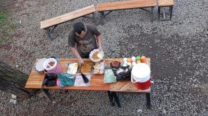 a man sitting at a picnic table with food on it at Tepian Pinus Glamping in Palayangan