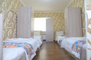 eine Reihe von Betten in einem Zimmer mit gelber Tapete in der Unterkunft GUEST HOUSE Silver1 in Samarkand