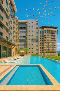 Una piscina con sombrillas volando en el aire sobre los edificios. en The persimmon condominium studio, en Cebú