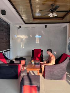 a man sitting in a room with a table and chairs at Naughty Nest Hostel Bali in Canggu +38 photos