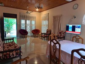 a bedroom with a bed and chairs and a tv at Shady Homestay in Matara