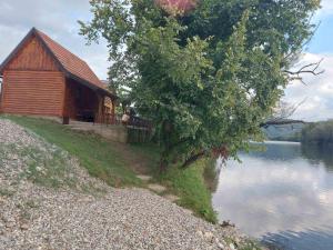 a wooden cabin next to a body of water at Vikendica Dani in Ljubovija