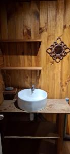 a bathroom with a white sink on a wooden wall at Oasis Tiny House & Tinaja in Pichare +14 photos