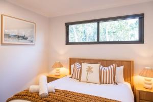 Un dormitorio con una cama con dos lámparas y una ventana. en Solara Escape - A laid-back and luxurious beach bungalow, en Margaret River Town