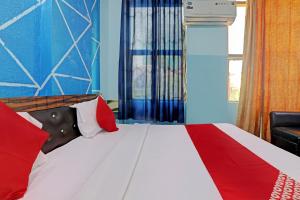 een slaapkamer met een rood-wit bed en een stoel bij Hotel O White Swan in Vibhuti Khand +17 foto's