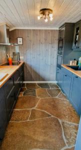 a kitchen with blue cabinets and a stone floor at Mountain Cabin With Panoramic Views In Brakastølen in Ron +26 photos