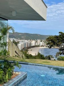 a swimming pool with a view of a beach at Varanda com Vista Mar - Cristo, Bondinho e Museu! in Niterói