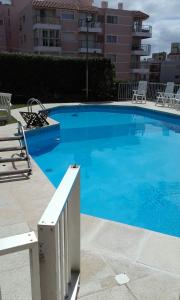a large blue swimming pool with chairs and a building at Guzmán in Punta del Este