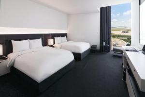 a hotel room with two beds and a large window at Hotel ORA Incheon in Incheon