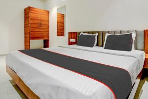 浦那Hotel O Haveli Executive的一间卧室，里面有一张白色的大床，配着黑色和灰色的枕头。