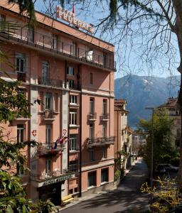 ein rosafarbenes Gebäude an der Straßenseite in der Unterkunft Hotel Federale in Lugano