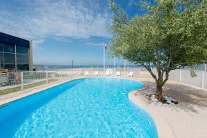 - une piscine avec un arbre à côté d'un bâtiment dans l'établissement Résidence L'Océane, Andernos, à Andernos-les-Bains