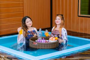 two girls standing in a swimming pool with a basket of fruit at Noura Resort Semporna in Semporna