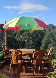 een tafel met een veelkleurige parasol en twee stoelen bij Mountain Paradise Homestay BATASIA LOOP in Darjeeling +32 foto's