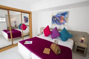 a bedroom with a large white bed with colorful pillows at Cristal Hôtel & Spa in Cannes